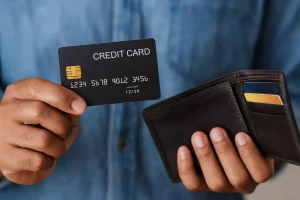 Person holding a credit card in South Africa with a brown leather wallet containing multiple cards.